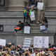Demonstrators watch the March for Our Lives from on top of a statue